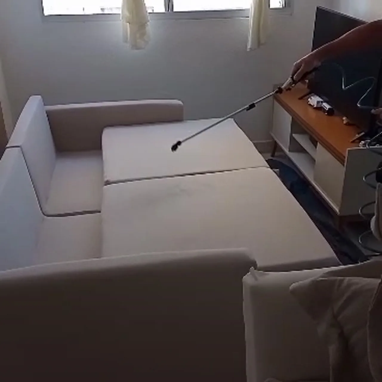 Lança de aplicação sobre o assento de um sofá claro, em uma sala