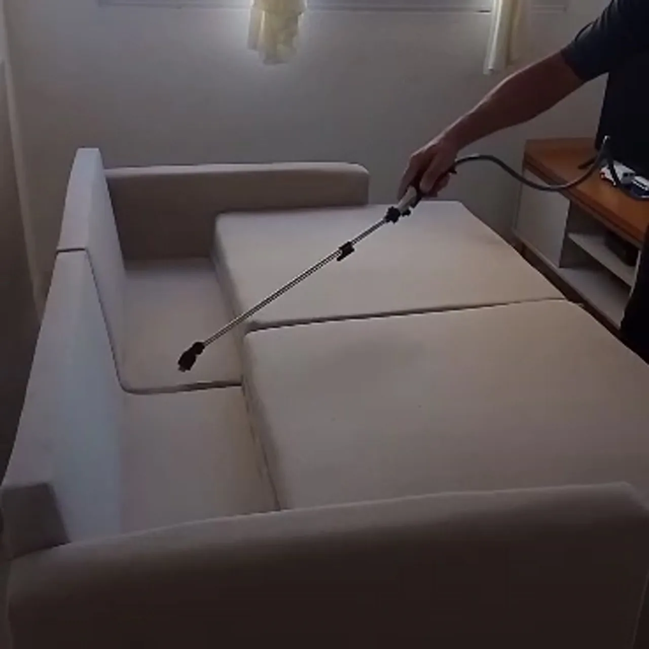 Fidelis aplicando impermeabilizante com a lança em um sofá bege